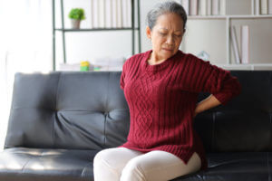 Elderly woman at home suffering from osteoporosis has back pain
